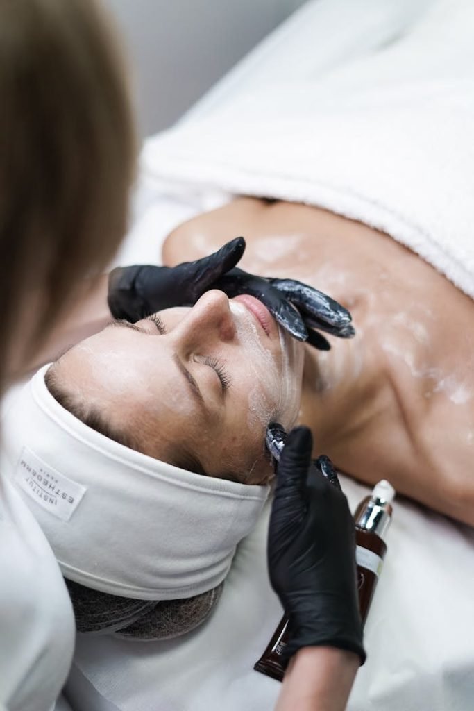 beautician-removing-clay-cosmetic-mask-from-woman-face-12115041 A relaxing skincare session with a woman receiving a facial treatment at a spa.